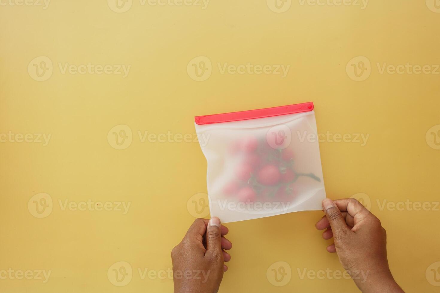 Hands holding a pouch with strawberries on a yellow background photo
