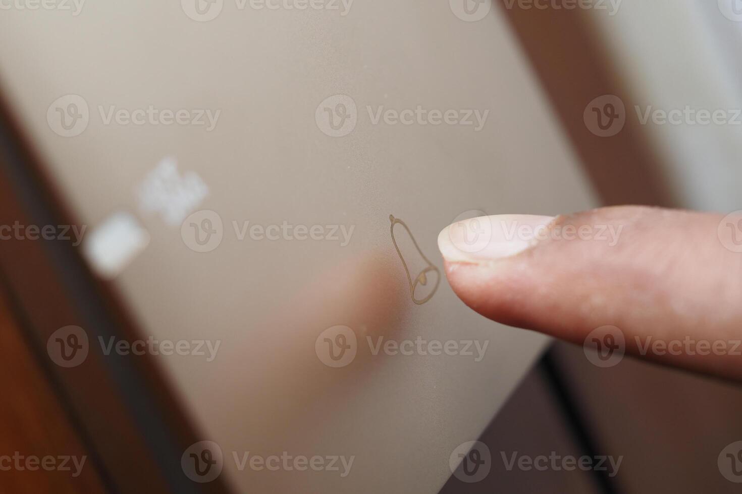 Finger tracing a simple drawing on a frosted glass surface photo