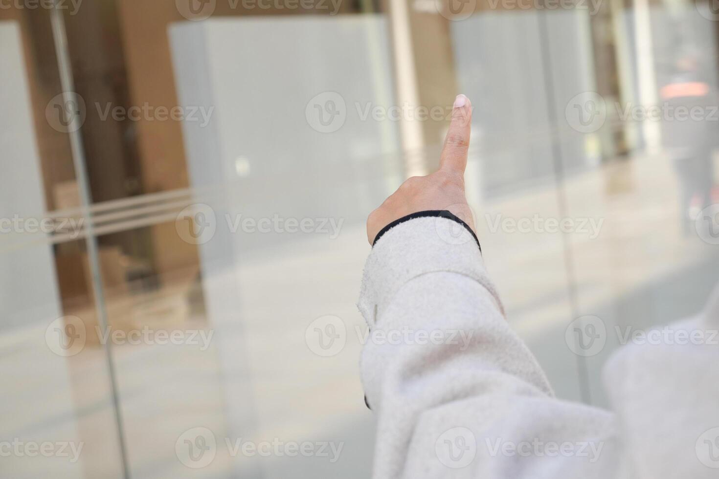 Person pointing at a transparent window in an urban setting photo