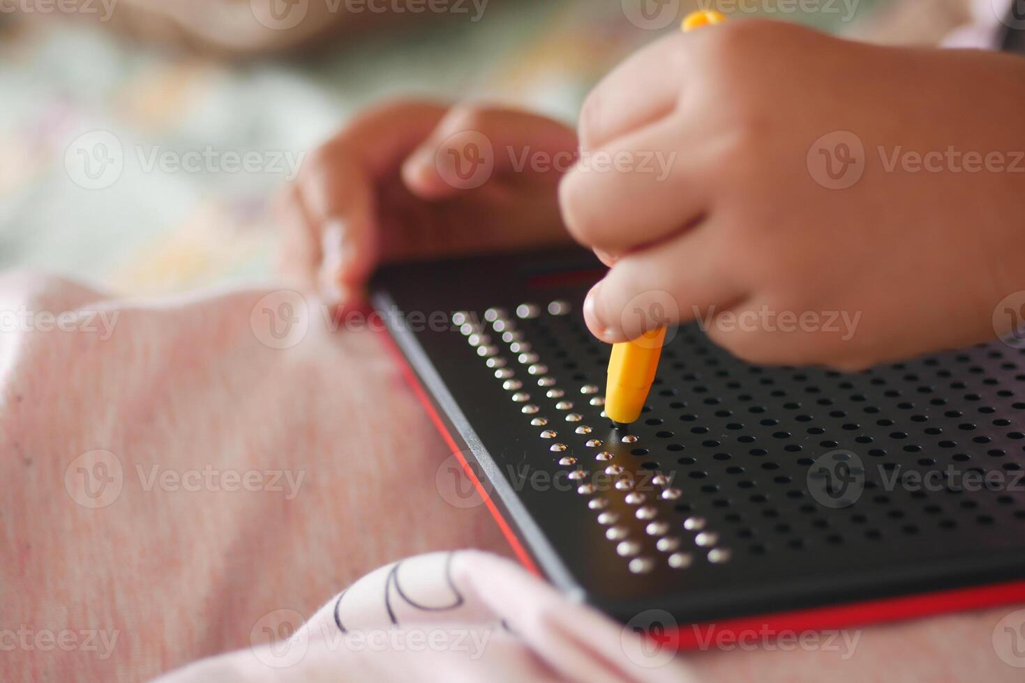 Child engaged in creative activity with a dot-matrix board at home photo