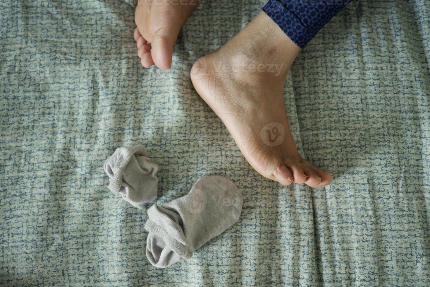 Barefoot on bed with a sock lying nearby during morning relaxation photo