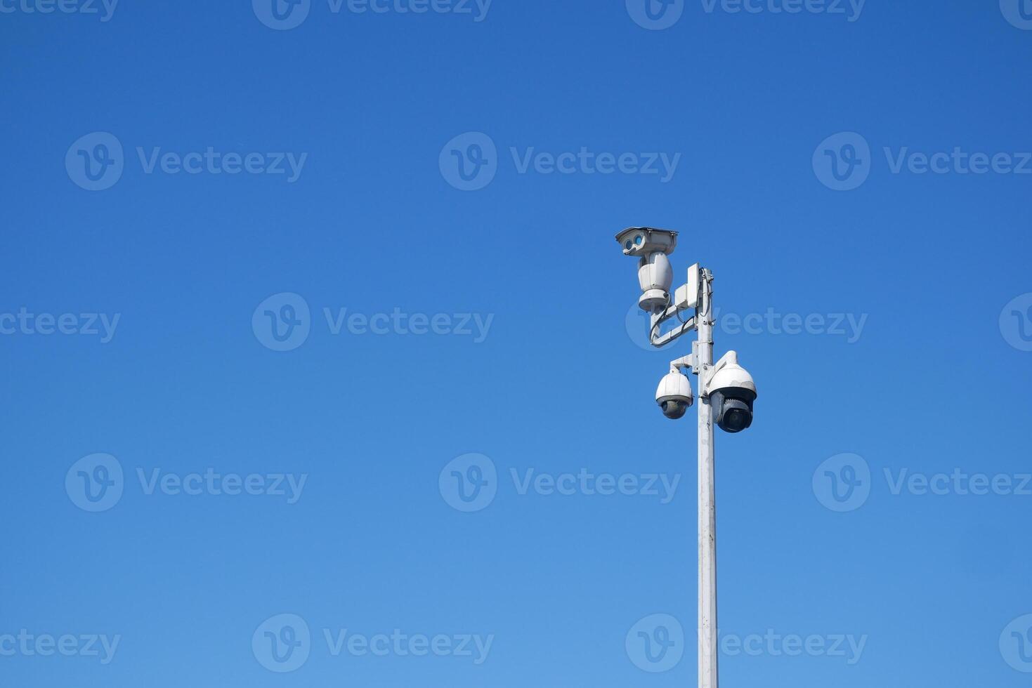 Security cameras mounted on a pole against clear blue sky photo