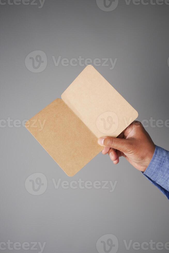 Hand holding open blank notebook with a gray background photo