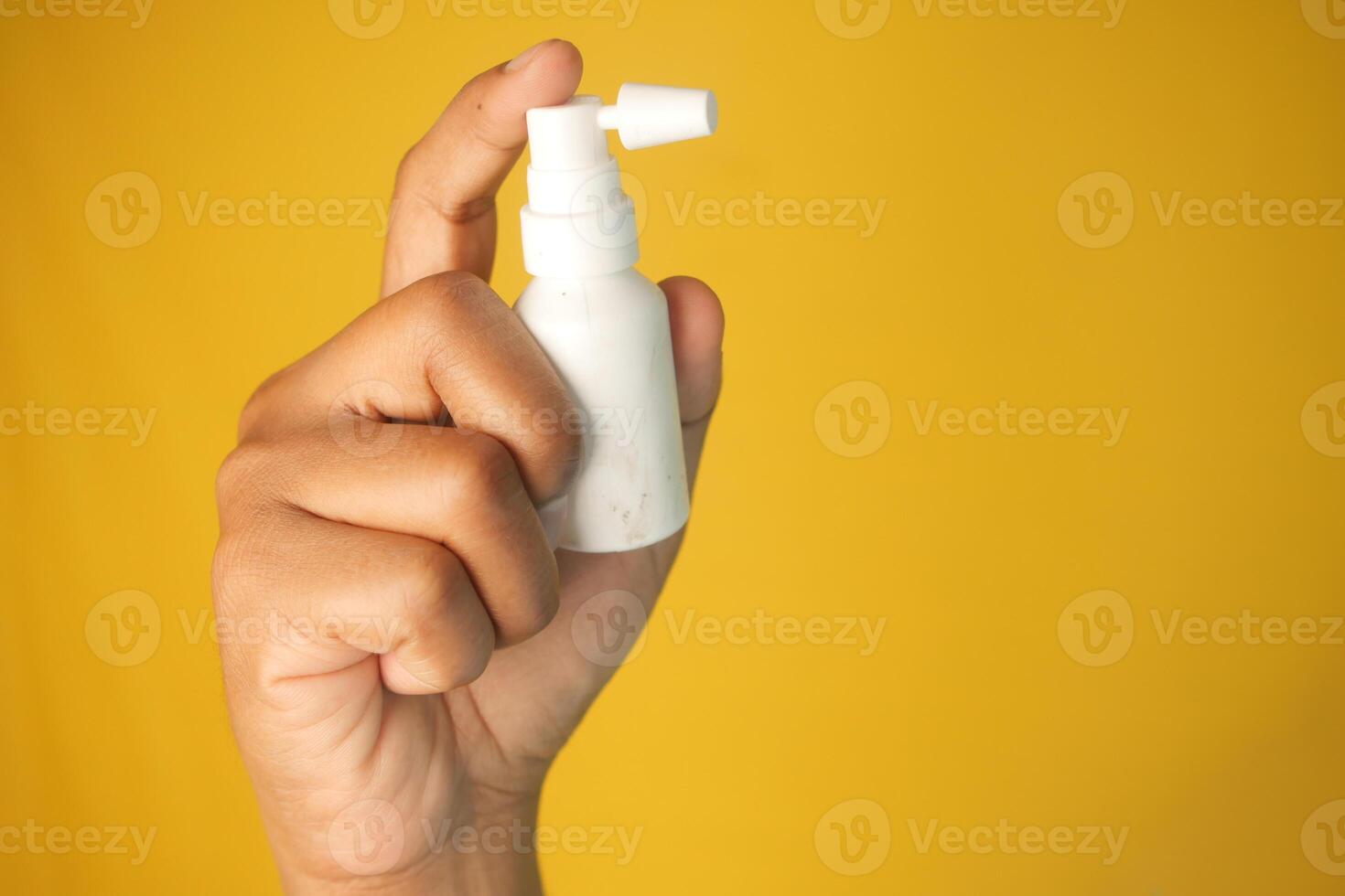 A hand holds a small ear spray bottle with a pump nozzle in focus photo