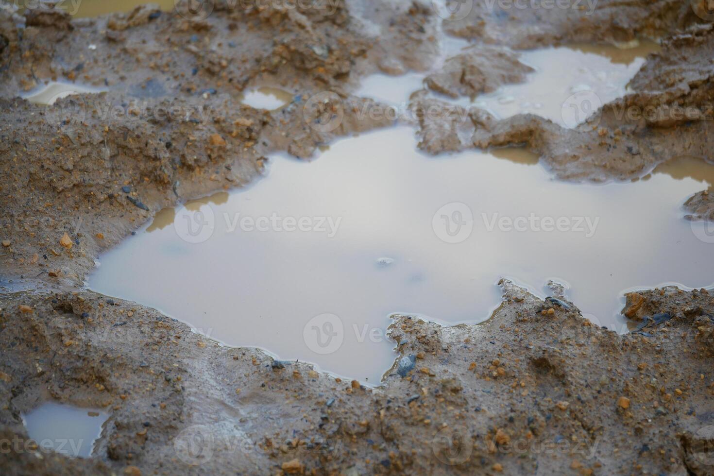 Mud puddle reflecting clouds after rain in rural area photo