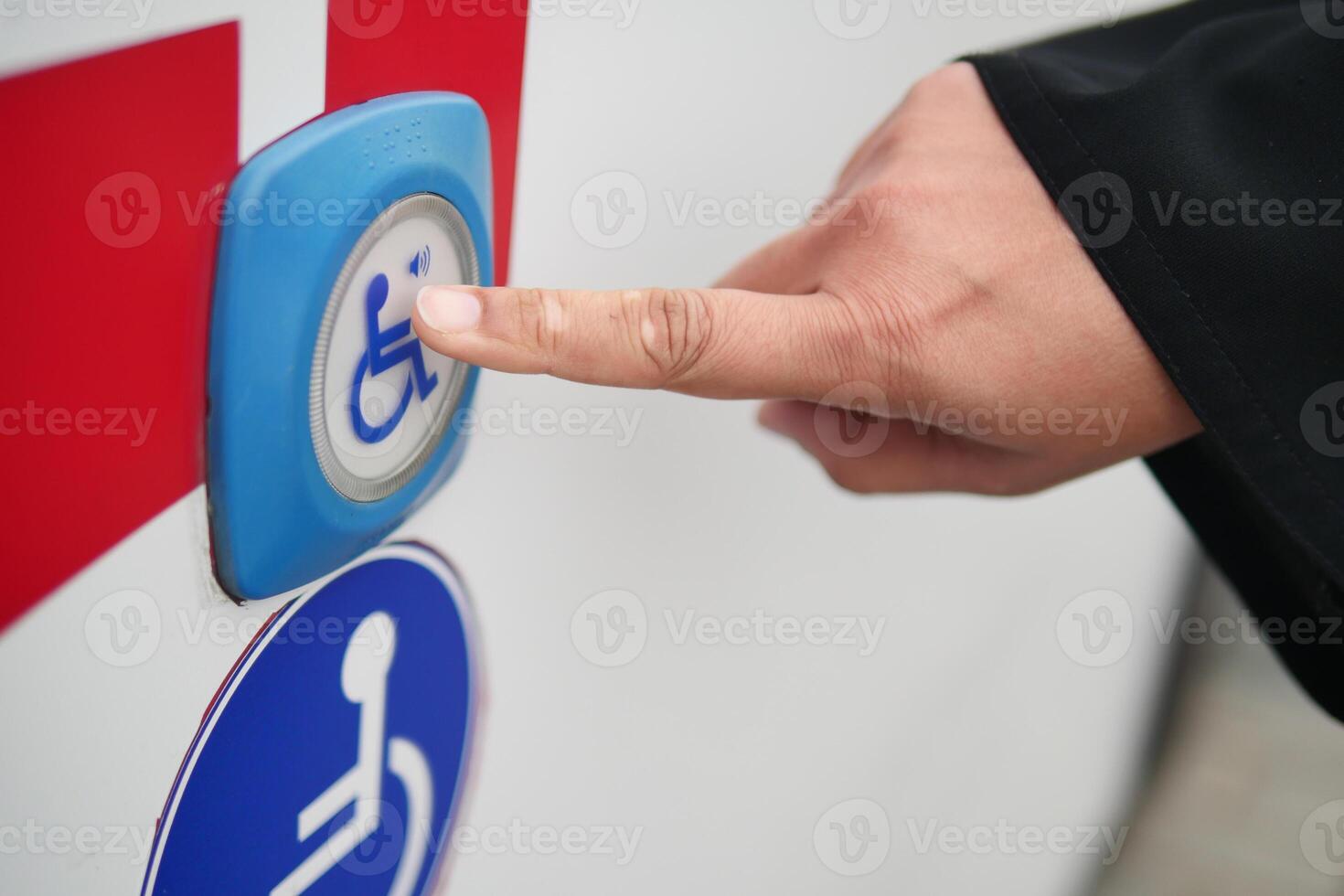 Hand pressing accessibility button on vehicle for assistance photo