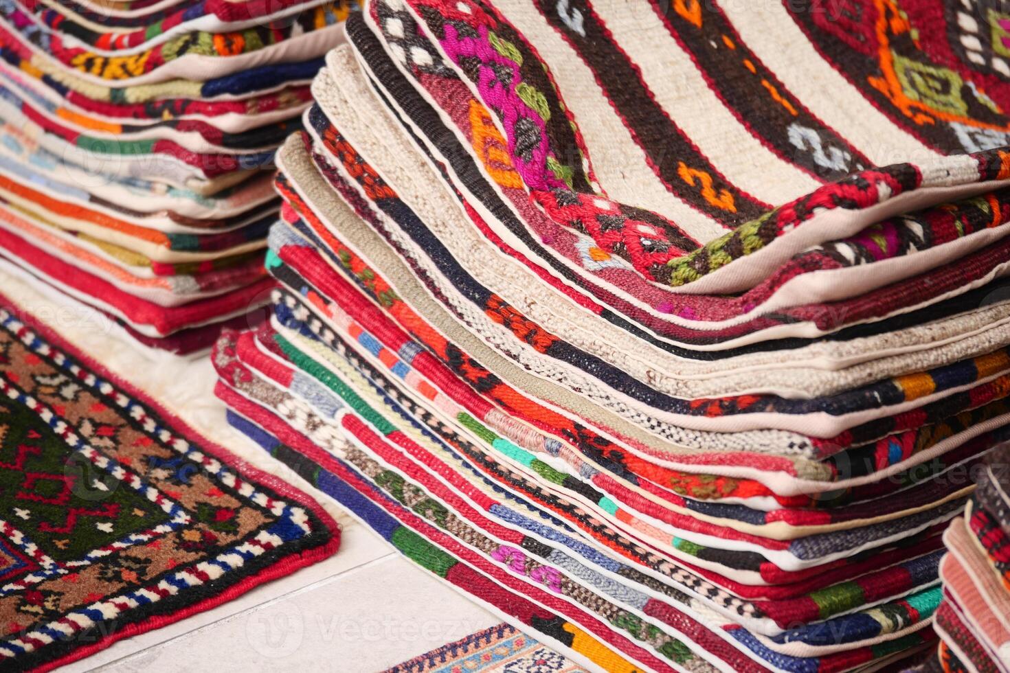 Colorful handmade rugs stacked neatly in a vibrant market setting photo