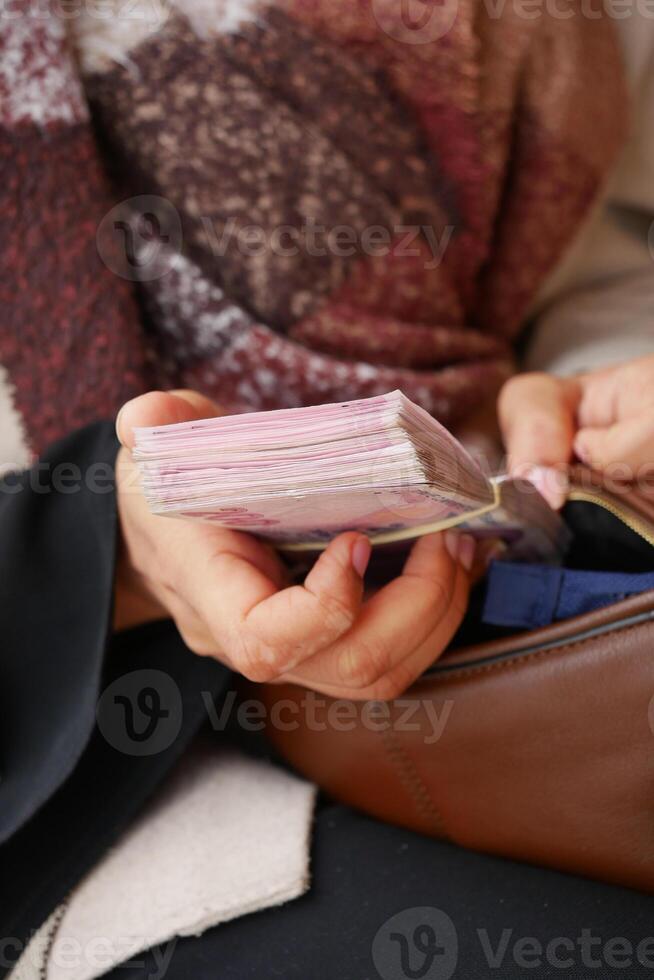 Person holding a stack of documents while seated in a public space photo