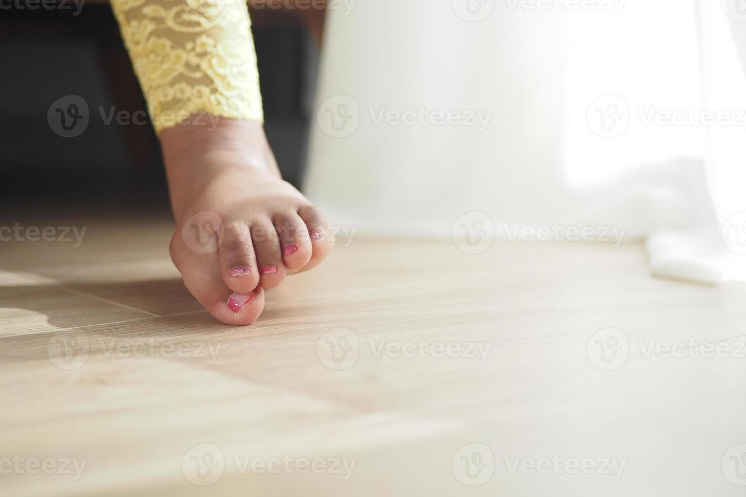 Child barefoot stepping on wooden floor in bright setting photo