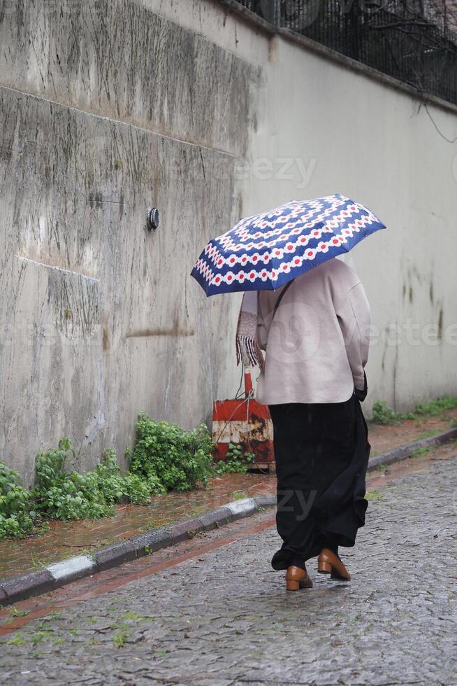 Person walking in the rain with an umbrella on a cobblestone street photo