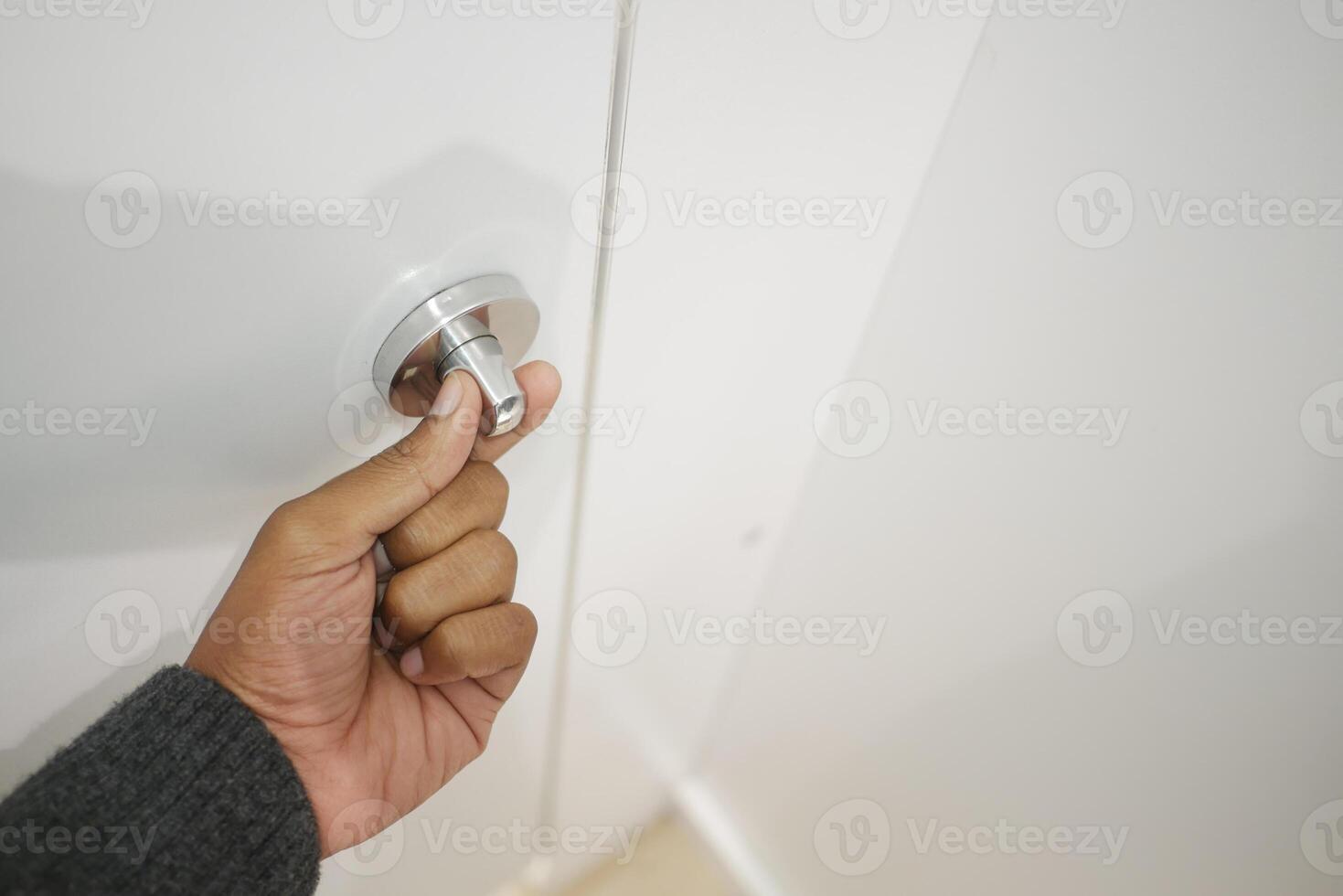 Hand turning a sleek silver door knob in a modern interior photo