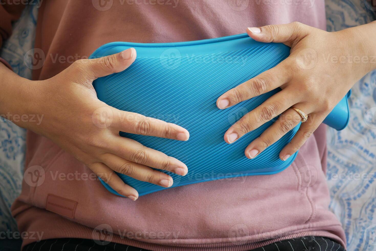 Woman resting with heating pad on abdomen for relief in cozy setting photo