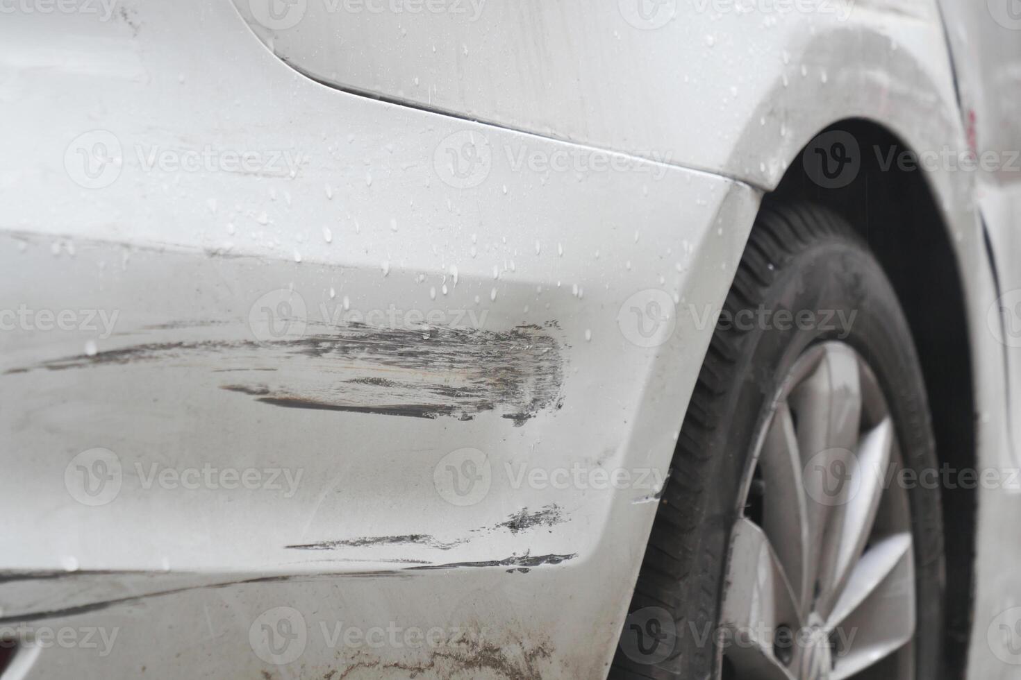 Car with paint scratches parked in rainy weather photo