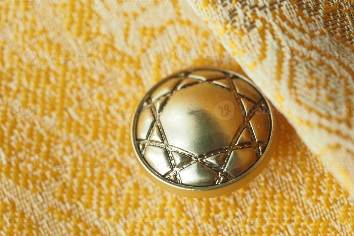 Decorative golden button with intricate design on vibrant fabric photo
