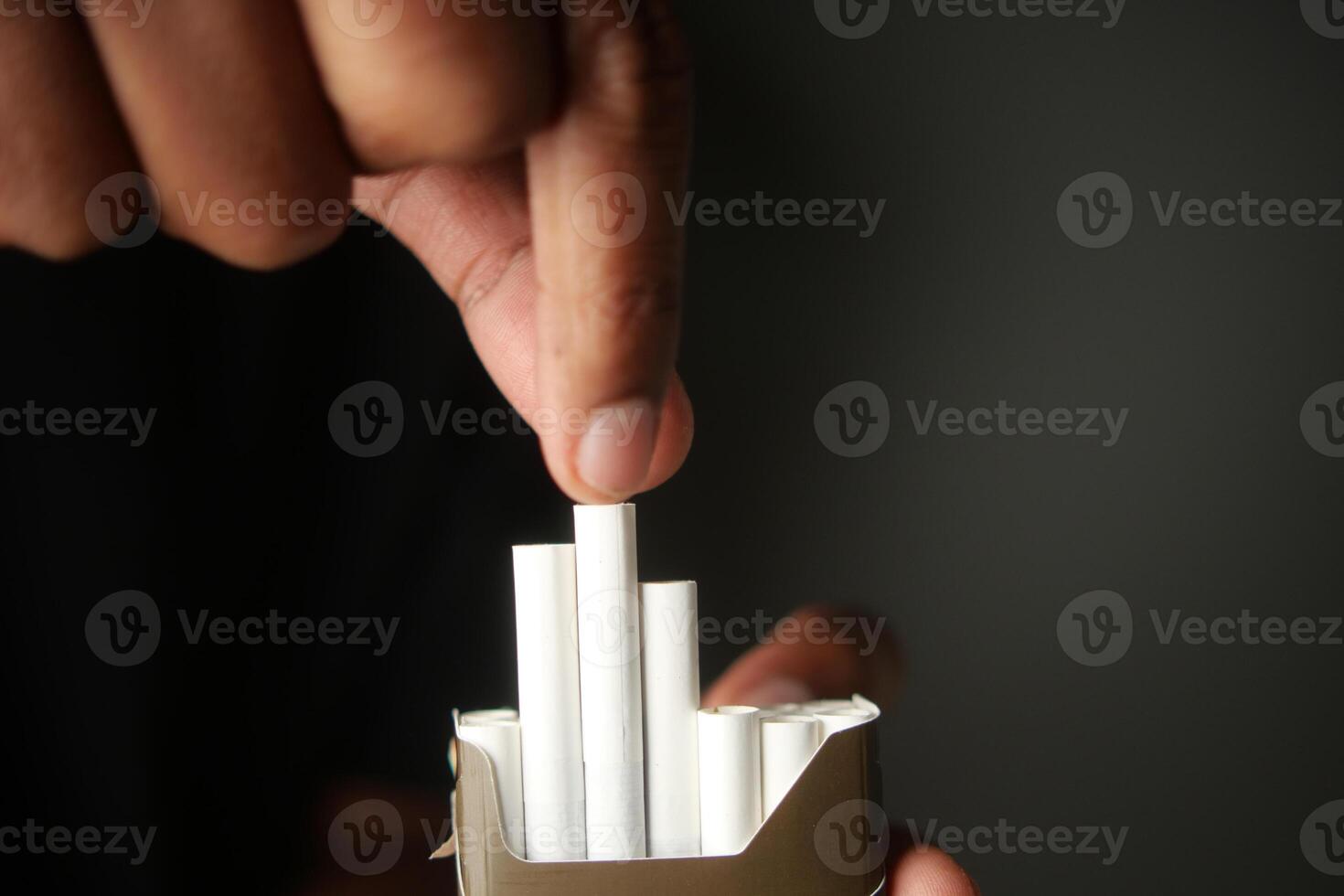 Person placing white tubes into a container in a dimly lit setting photo