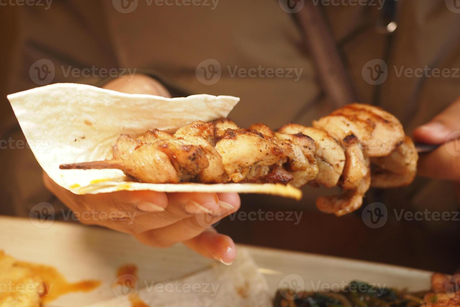 Grilled chicken skewer being served with flatbread at local eatery photo