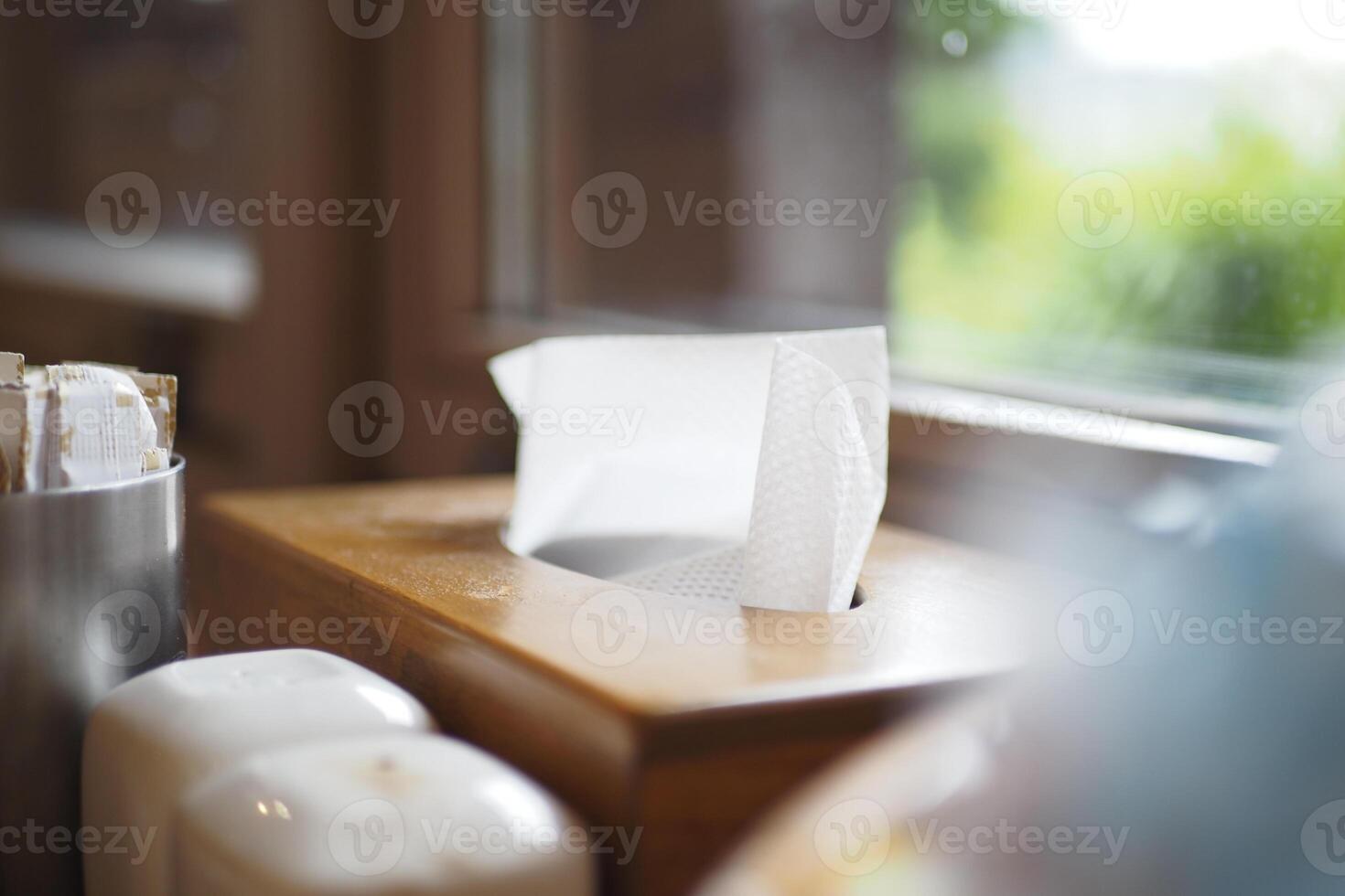 Tissue box and dispenser near window in a cozy restaurant setting photo