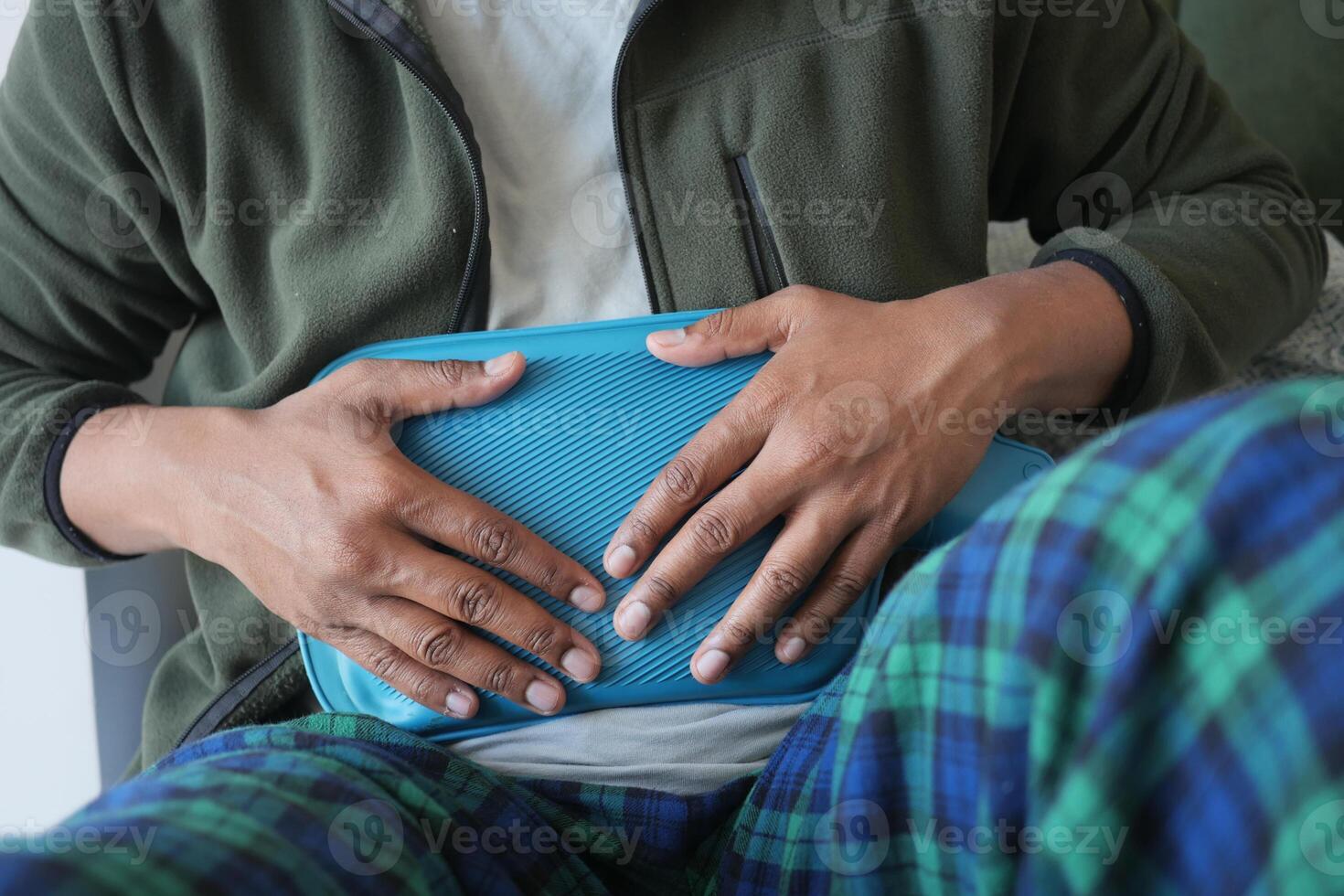 Individual using a heating pad on their stomach while sitting comfortably photo