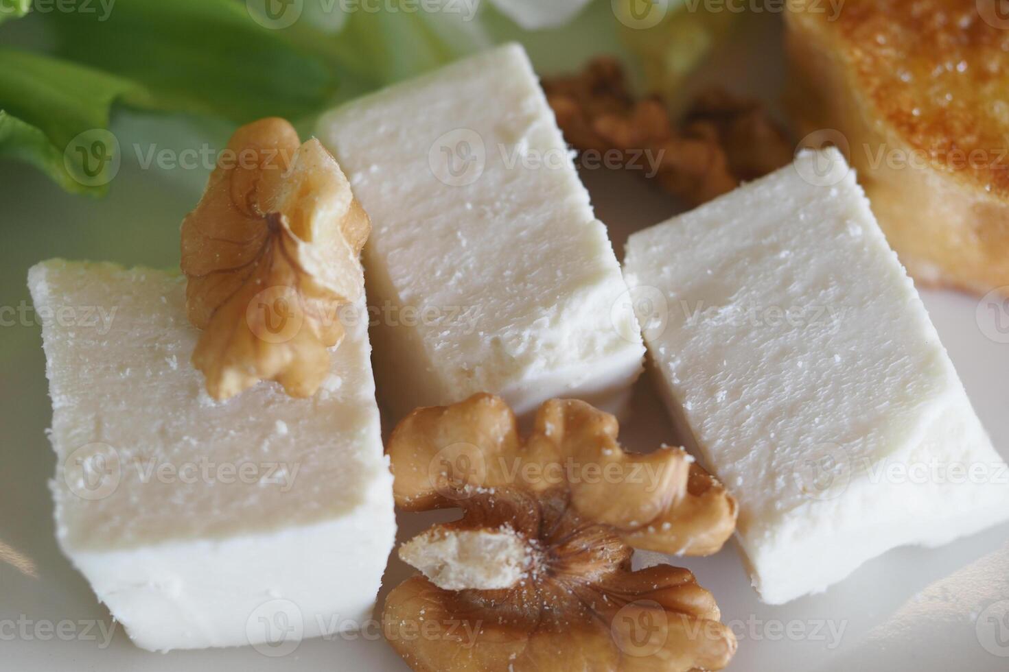 Soft cheese and walnuts served on a plate with fresh greens photo