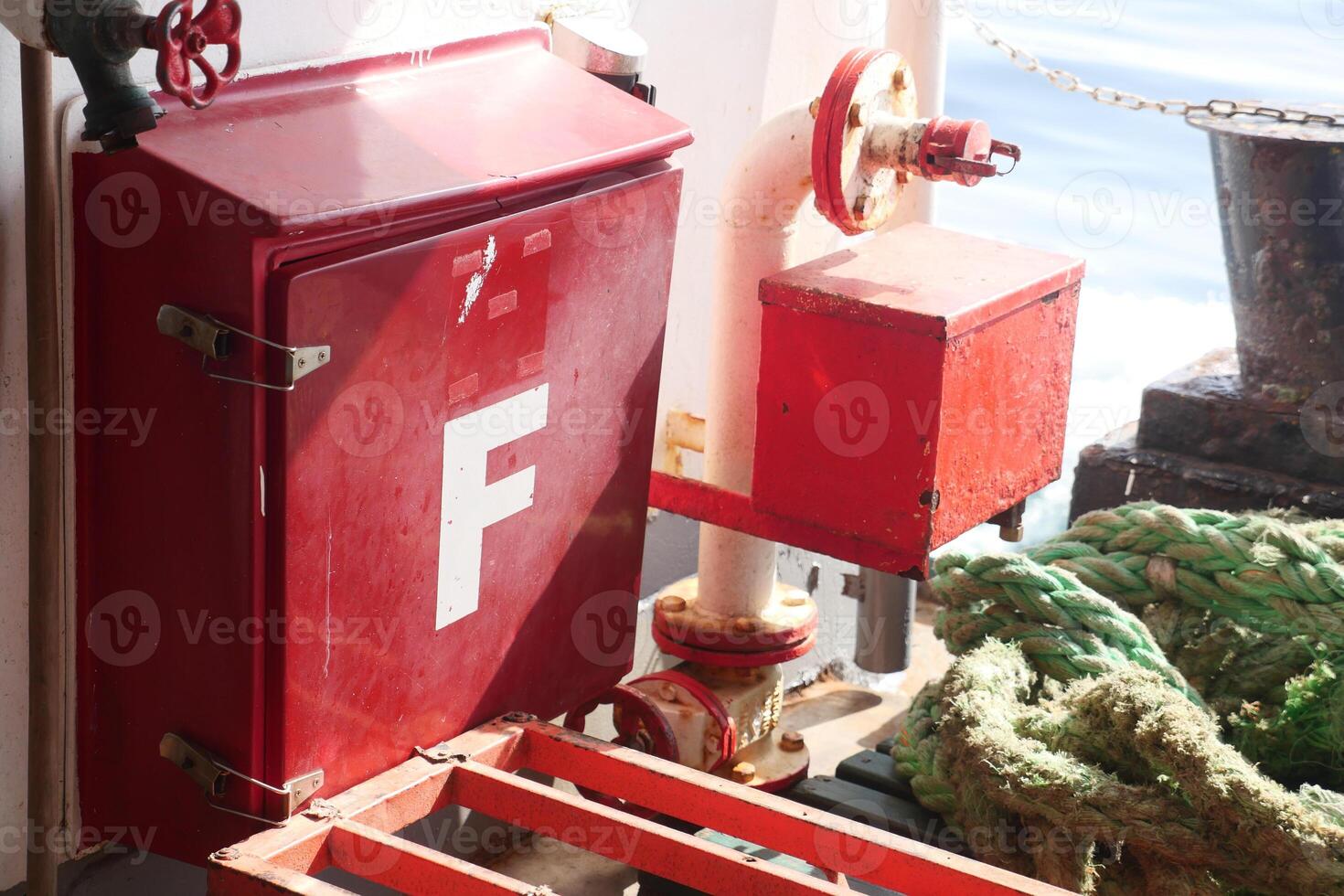 Red fire box and equipment on a ship near the ocean photo
