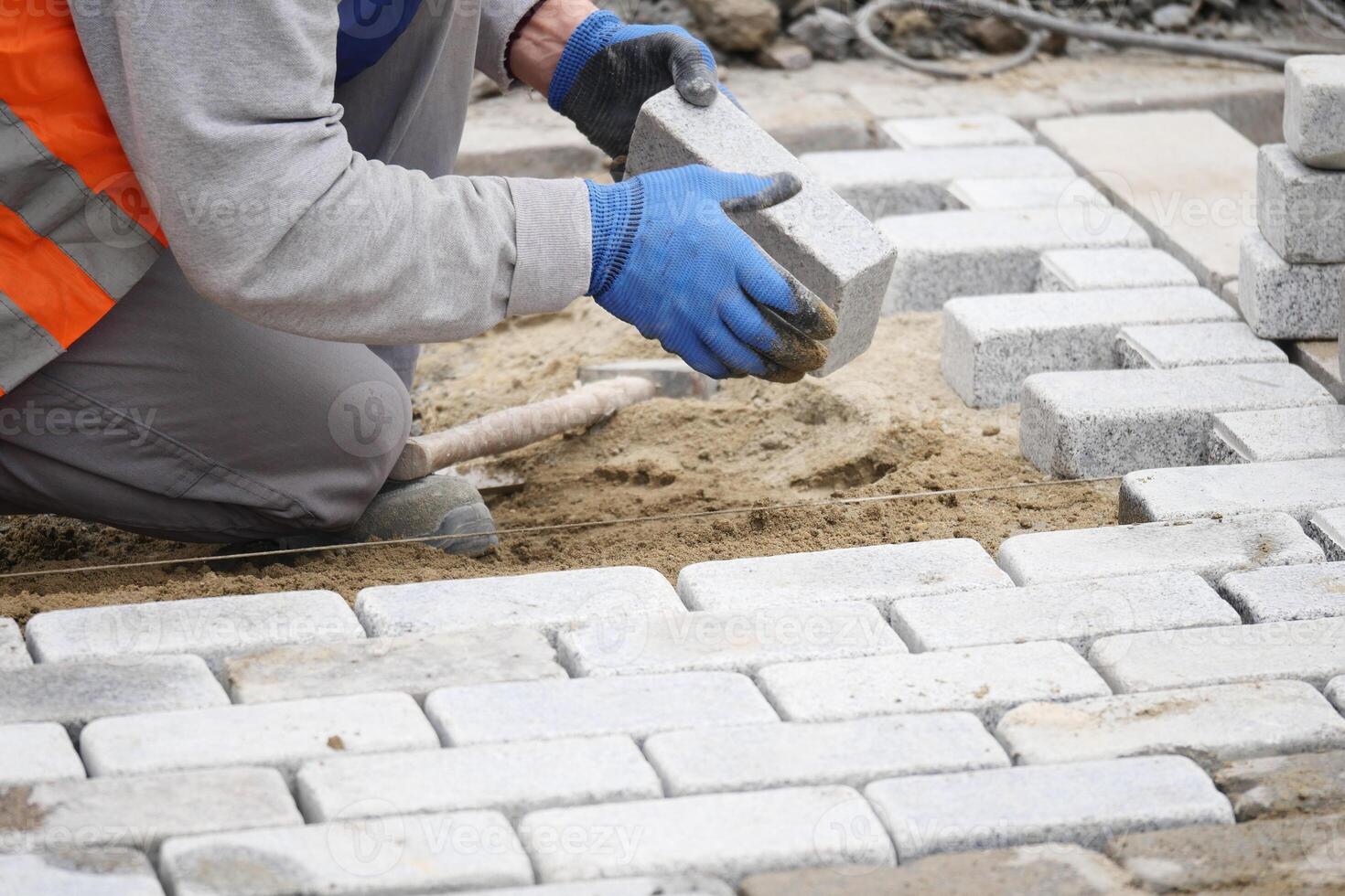 Worker installing stone pavers on a construction site photo