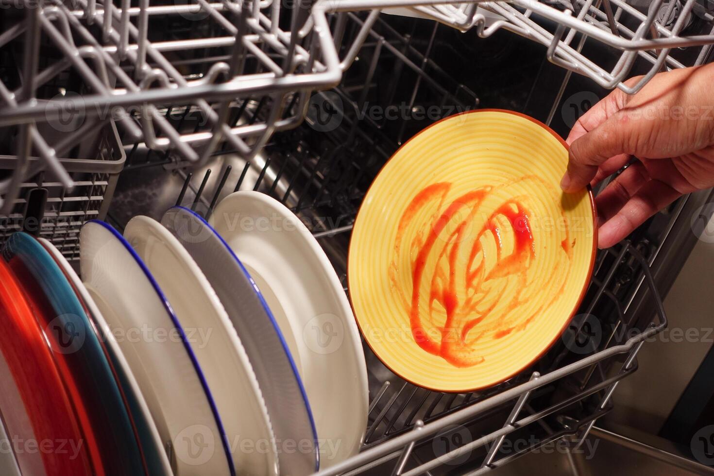 Cleaning dirty dishes in a dishwasher during evening hours photo