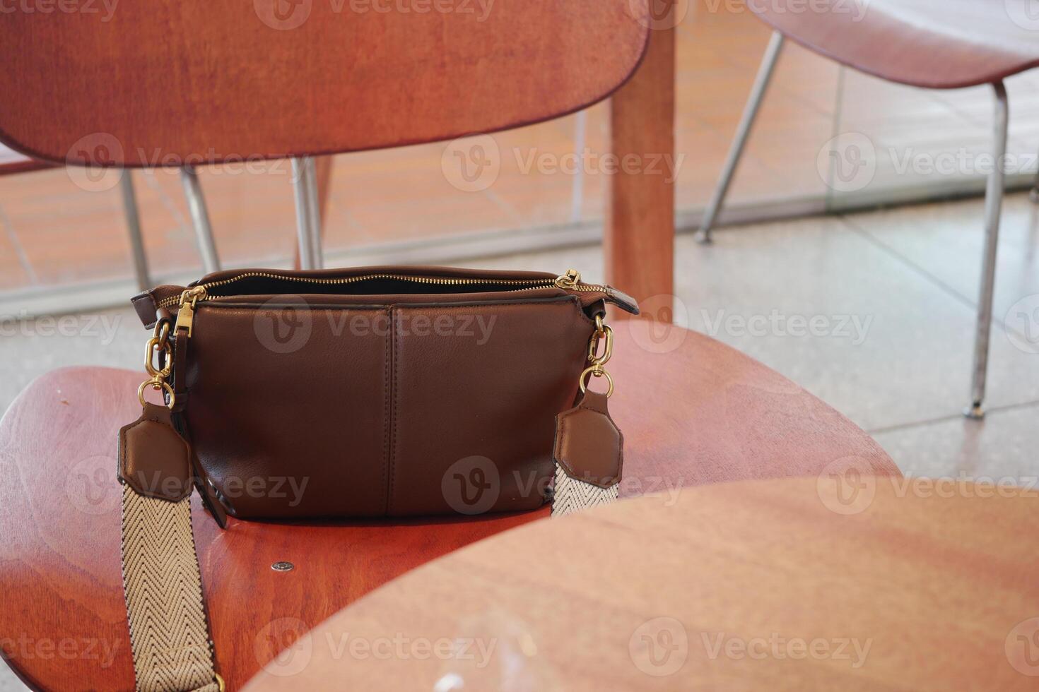 brown bag rests on a wooden chair in a cafe. lost bag concept photo