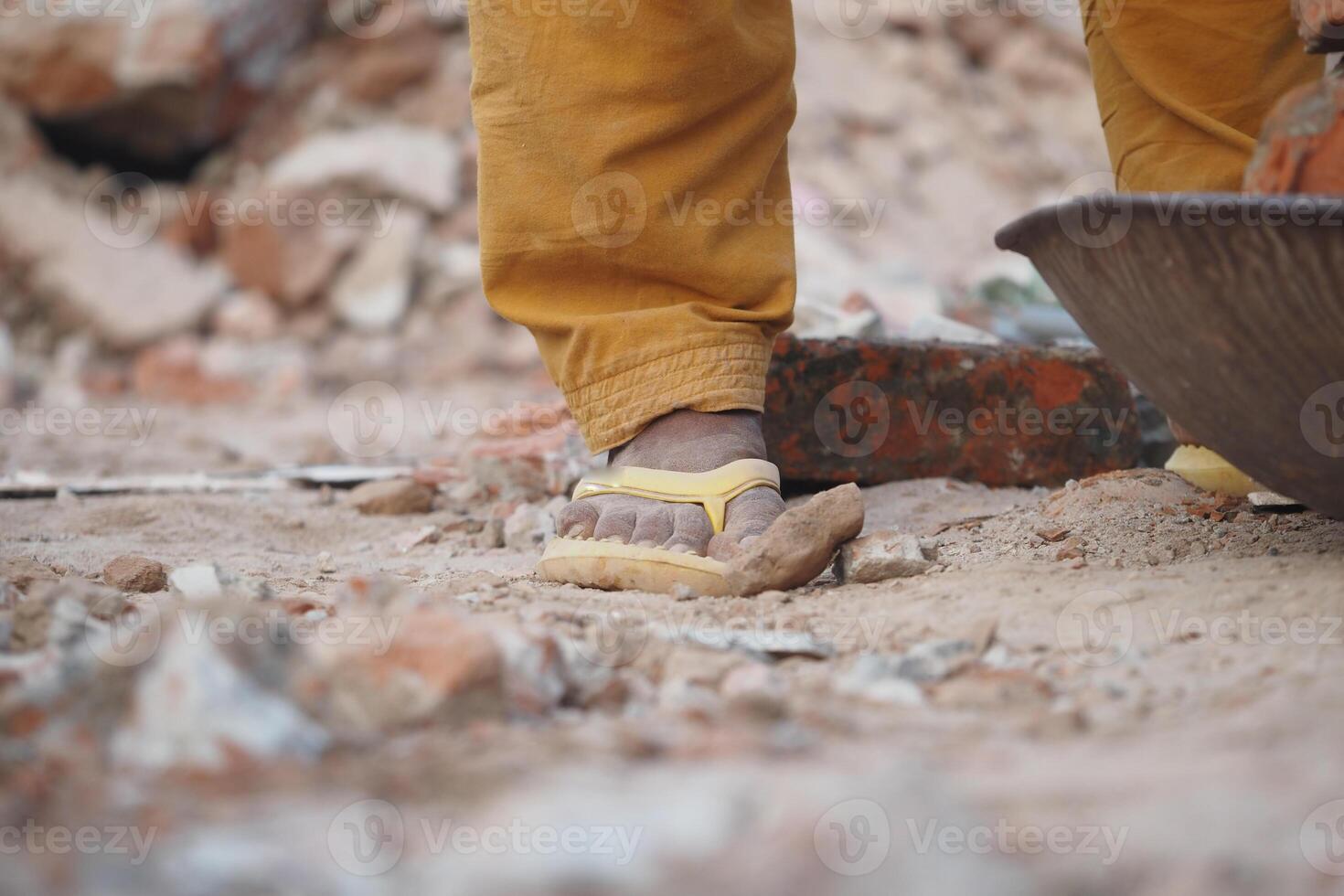 Construction worker in sandals navigating rubble at a building site photo