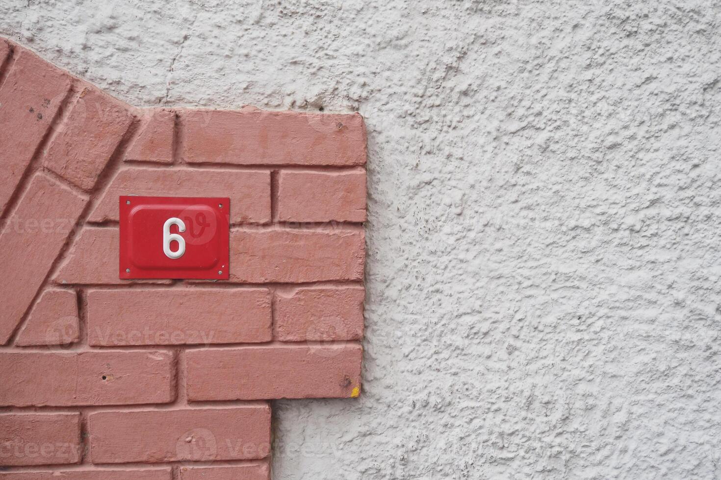House number six displayed on a textured wall surface photo