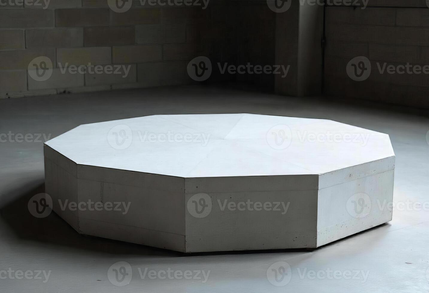 A white dodecagon platform in a room with concrete walls and floor, the background is dark photo