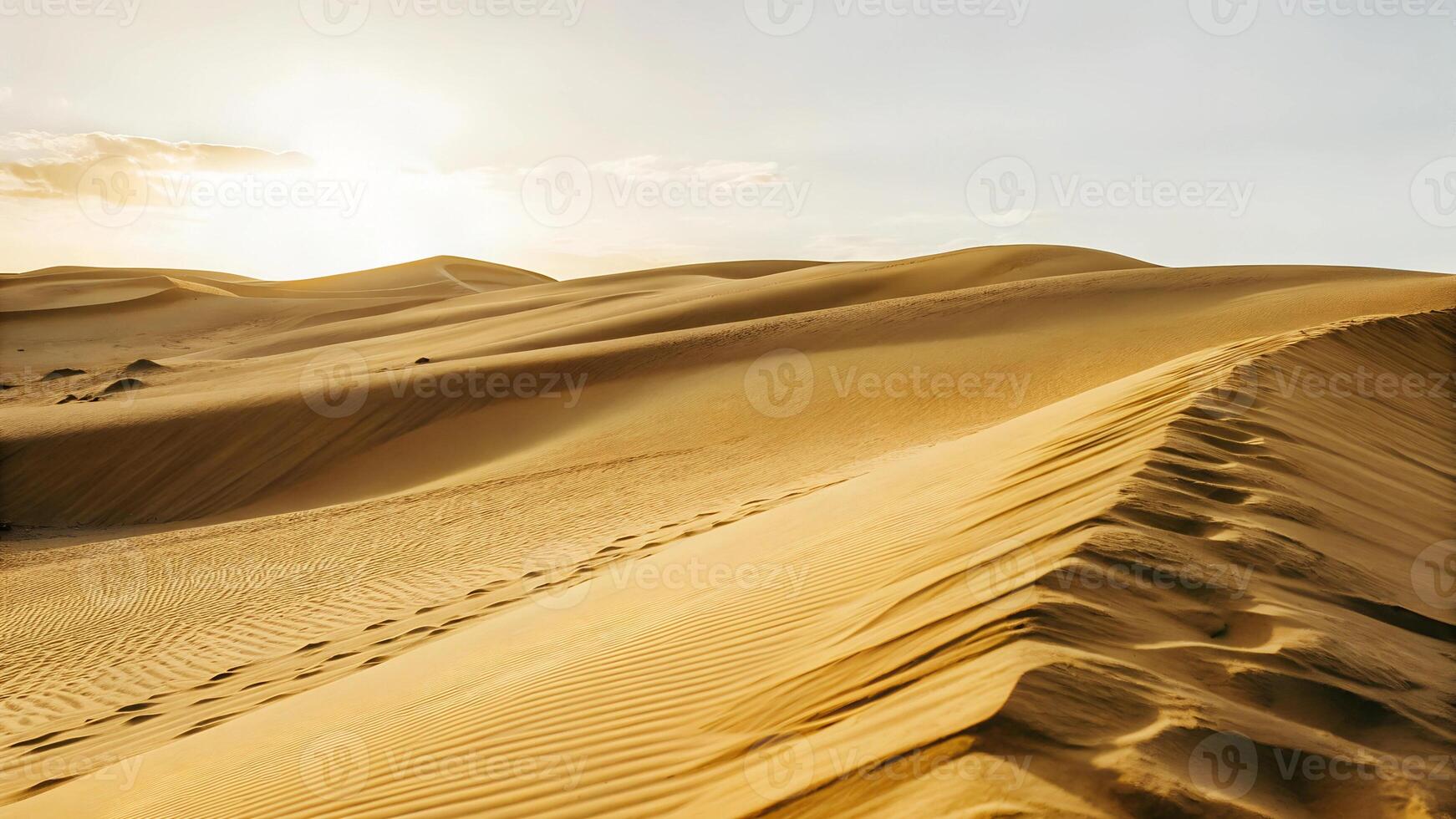 Sand dunes with footprints in the desert under a clear sky, the warm sunlight casting shadows on the undulating landscape photo