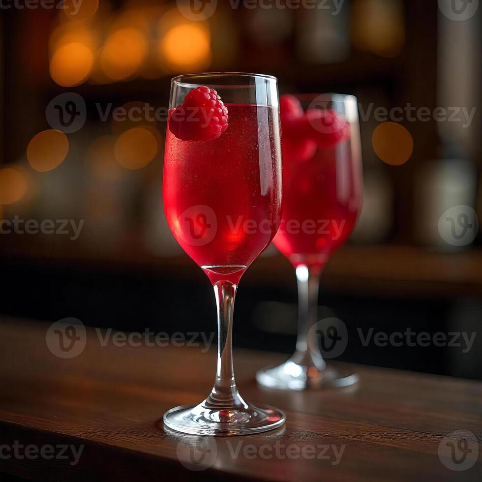 Two glasses of red cocktail with raspberries on a wooden bar with blurred bottles in the background photo