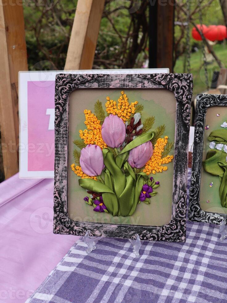 Exquisite Hand-Embroidered Tulip and Mimosa Artwork in a Decorative Frame. A close-up of a framed silk ribbon embroidery piece. photo