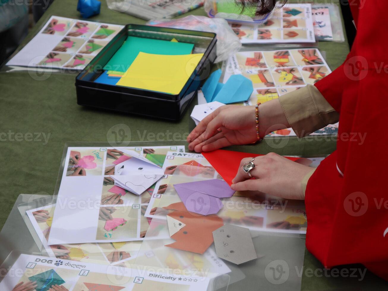 Hands Folding Origami Figures at a Workshop. Close-up of hands carefully folding origami, likely at a community workshop or craft fair. photo
