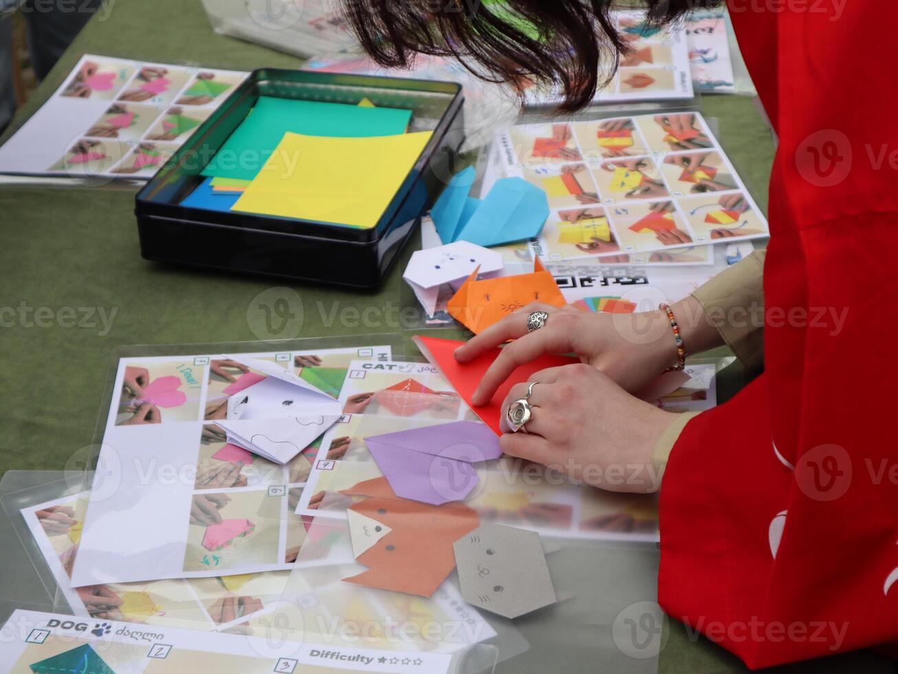 Hands Folding Origami Figures at a Workshop. Close-up of hands carefully folding origami, likely at a community workshop or craft fair photo