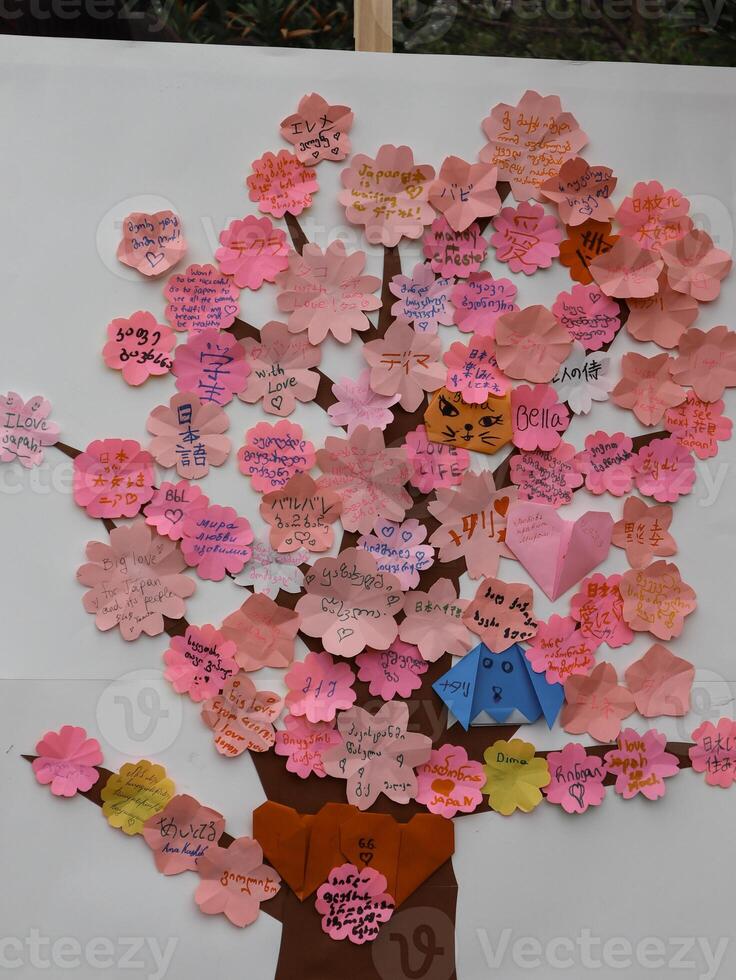 Messages of Support and Love for Japan, Displayed as a Cherry Blossom Tree. A large display, shaped like a cherry blossom tree, is adorned with numerous small, folded paper notes. photo