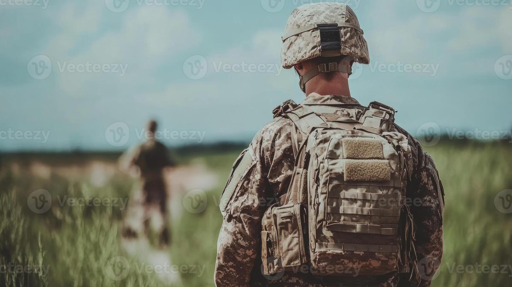Two soldiers move through tall grass in a training exercise under a bright blue sky photo