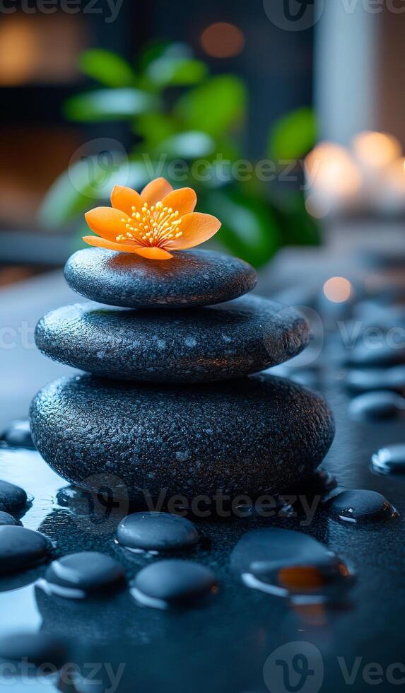 Stones and flowers in harmony. Three smooth stones stacked with an orange flower on top, creating a serene atmosphere in a tranquil setting. photo
