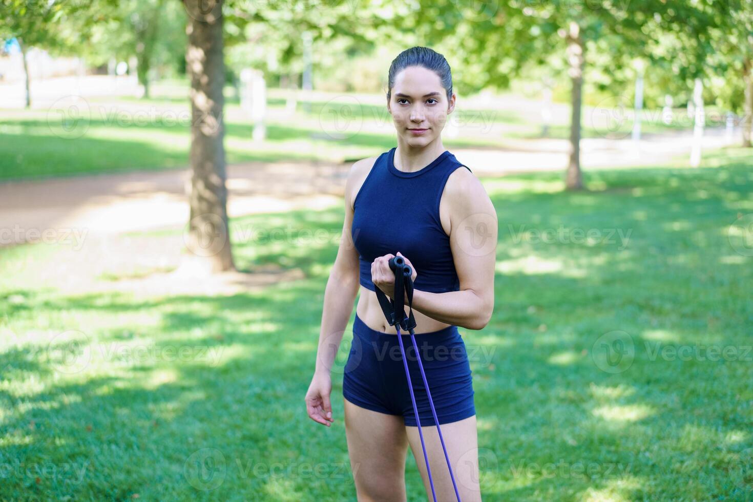 Woman in park, working out with resistance bands, showing commitment to fitness and dedication to exercise routine photo