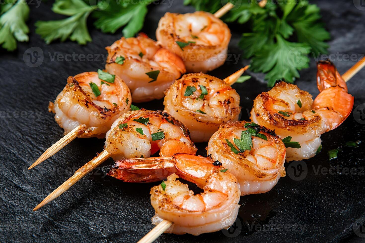 Grilled shrimp skewers with herbs on black slate. photo