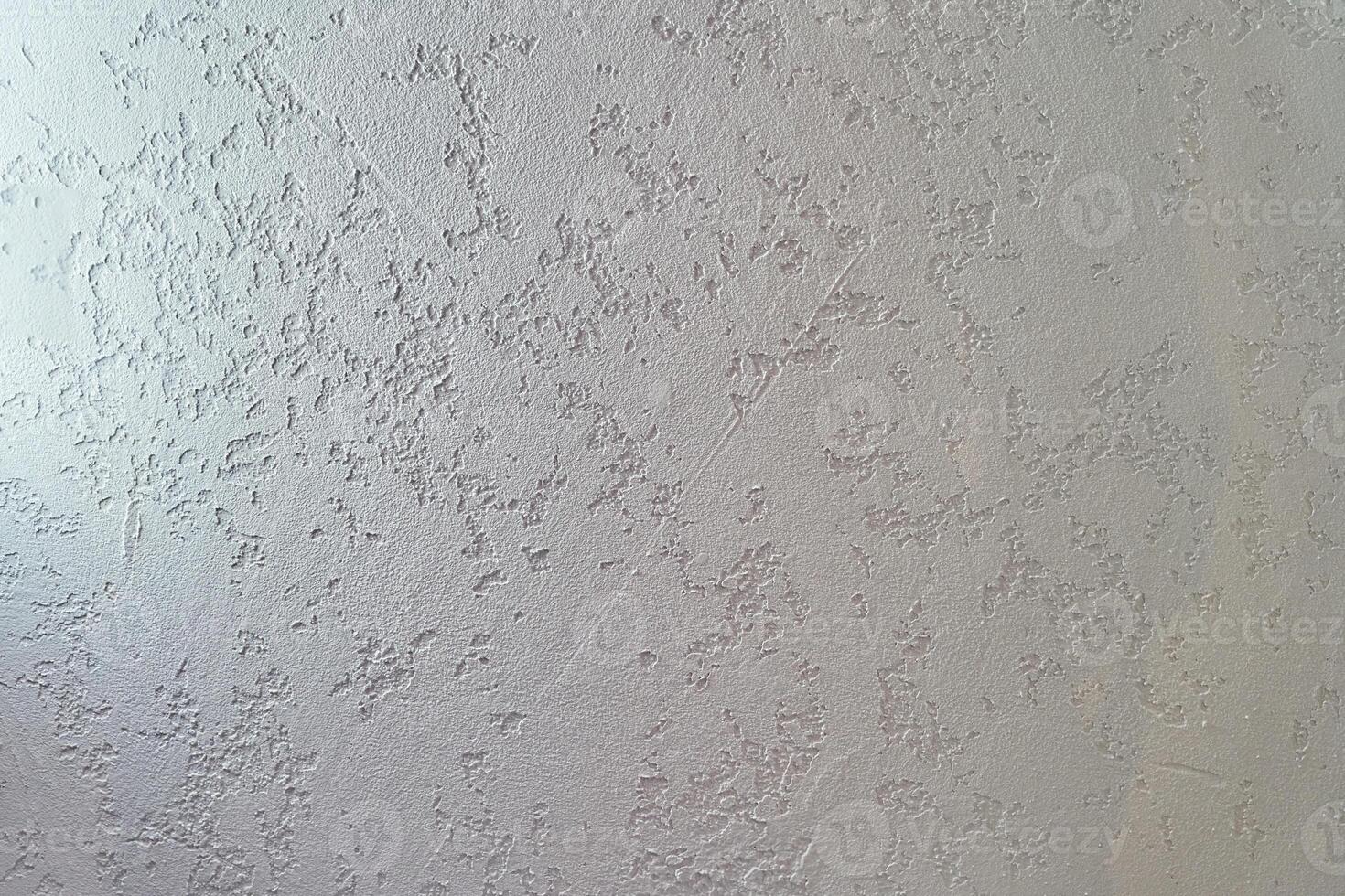 Uneven background with the texture of decorative plaster painted in white concrete wall. Rough wall with space for copying photo