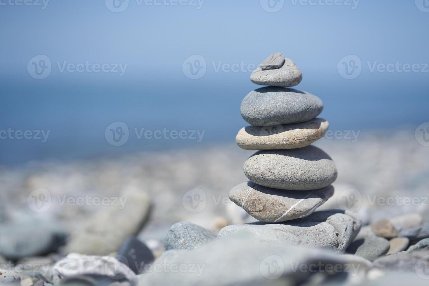 Balancing rocks on a pebble beach during sunset. Smooth pebbles on the beach against the background of the sea and sunlight, creating a side effect on the water photo