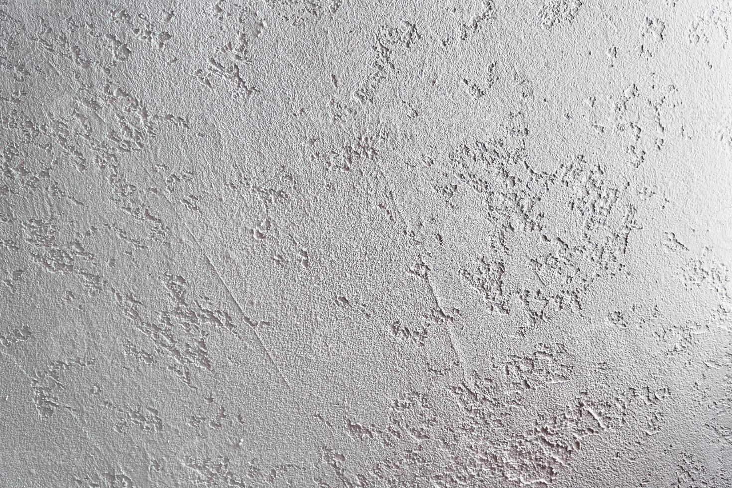 White plastered wall. Uneven background with the texture of decorative plaster painted in white concrete wall. Rough wall with space for copying photo