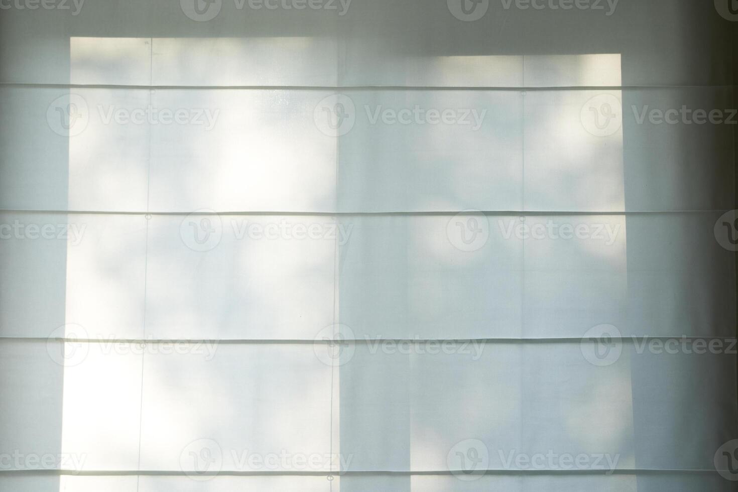 Soft sunlight penetrates inside, casting an elegant shadow of leaves on the blinds, emphasizing the warm neutral tones. photo