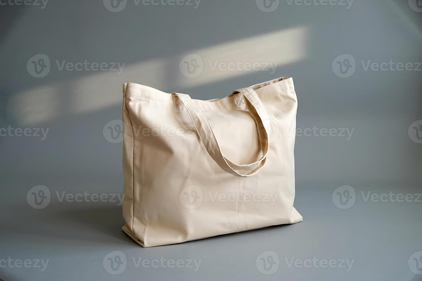 Beige cotton tote bag on a grey background with soft sunlight, minimal style photo