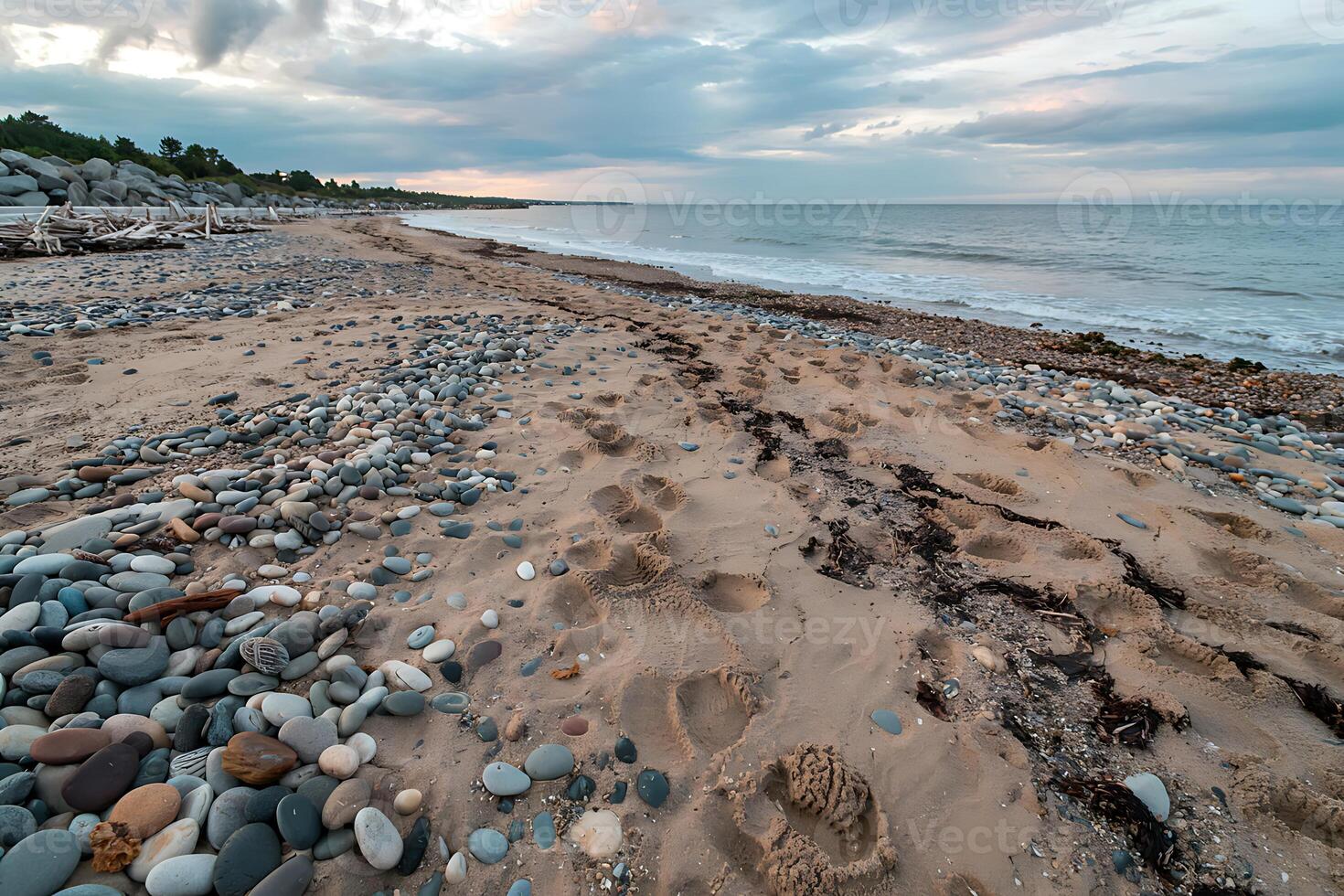 Coastal serenity merging pebbles footprints and horizon under a soft cloudy canvas photo