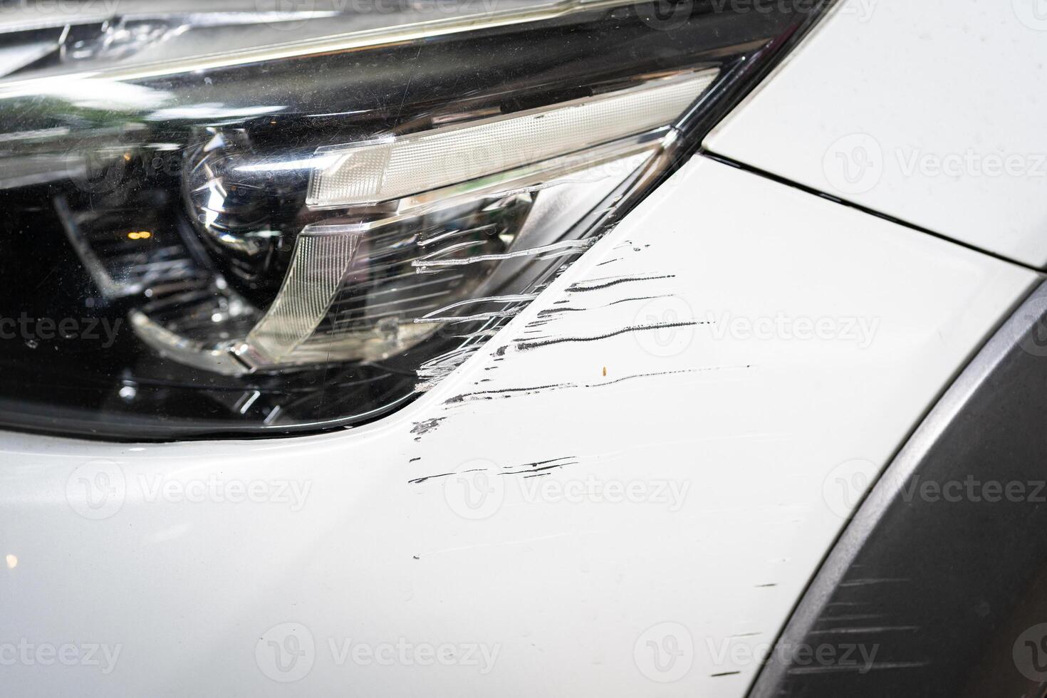 Small scratch on car front bumper close up. Claim and insurance concept. Car with scratched bumper paint and dented parts on the side. photo