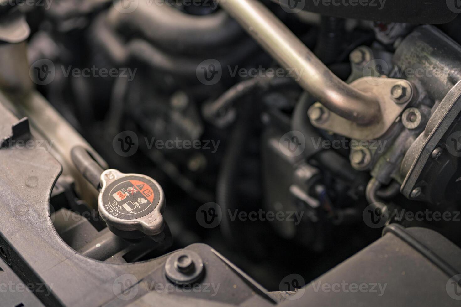 Close up of a vehicle coolant reservoir cap and surrounding engine components. Car engine radiator cap. photo