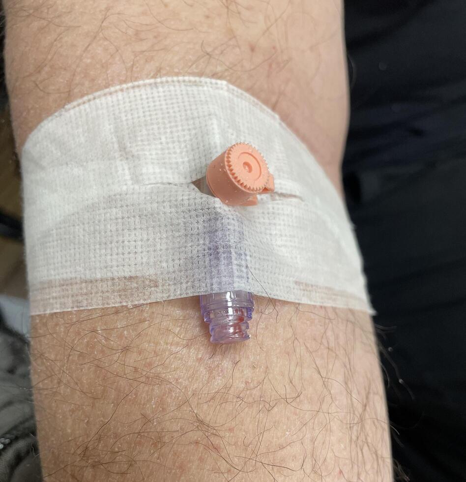Intravenous IV line secured to a persons arm with a white gauze dressing. photo