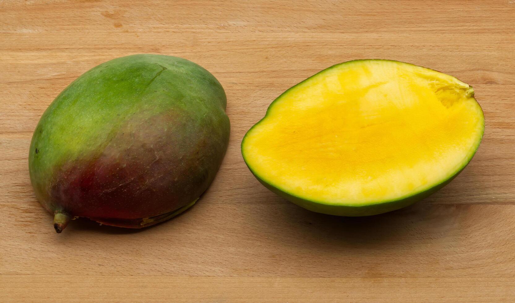 Ripe Mango, Whole and Halved, on Wooden Surface photo